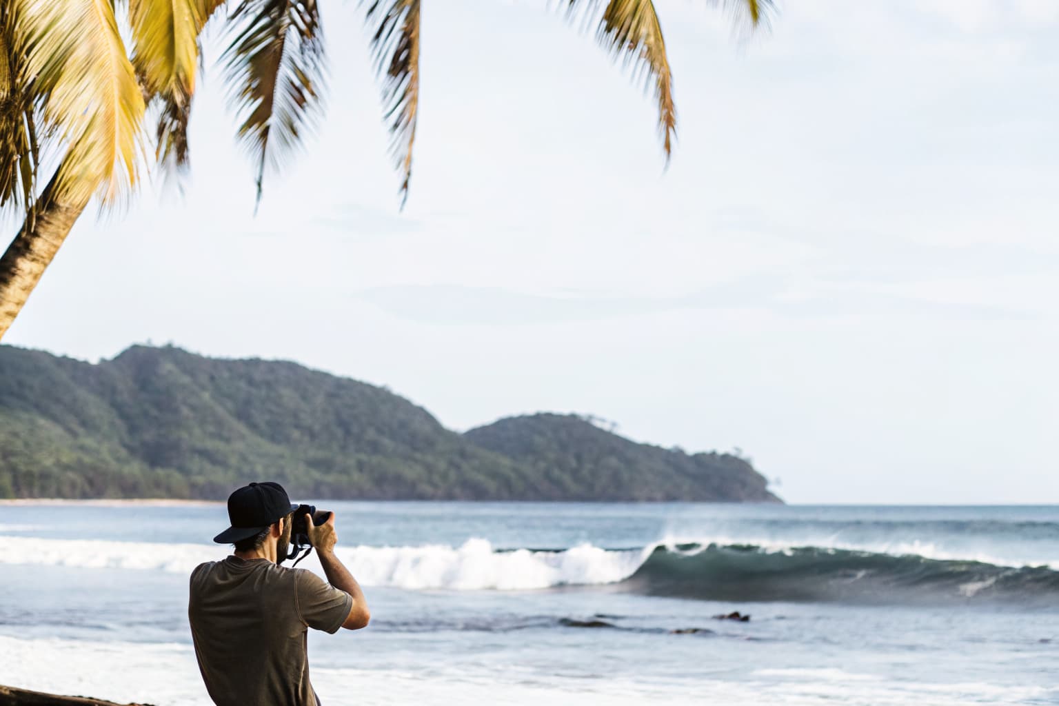 Lush green Costa Rica coastline with palm trees and Pacific waves during green season