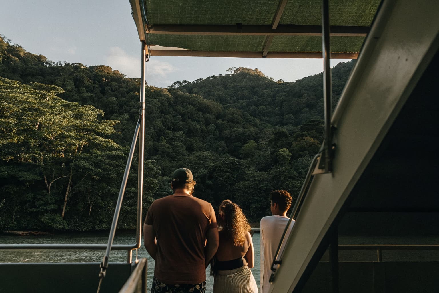 Group of friends looking out at the ocean from a boat near Jaco, Costa Rica with jungle-covered mountains in the background