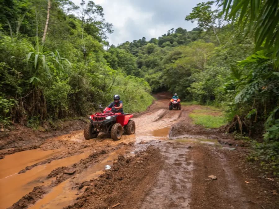 ATV riders navigating muddy jungle trails through the Costa Rican backcountry rainforest