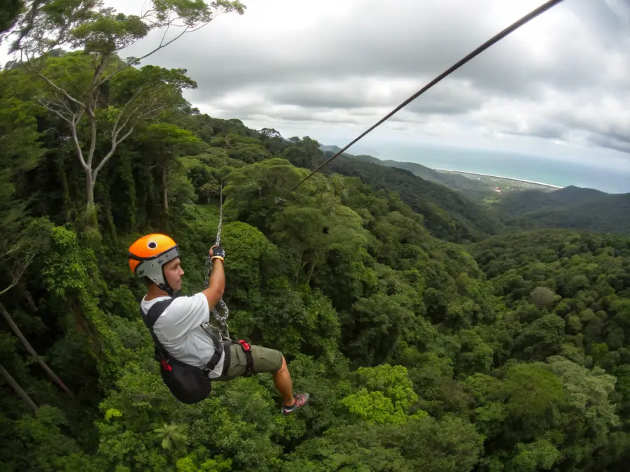 Adventurer ziplining through the jungle canopy above Costa Rican rainforest at Playa Hermosa